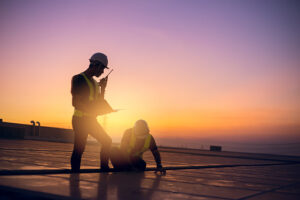 Two workers performing commercial roofing inspection in a scenic beautiful view at Jonesboro, AR